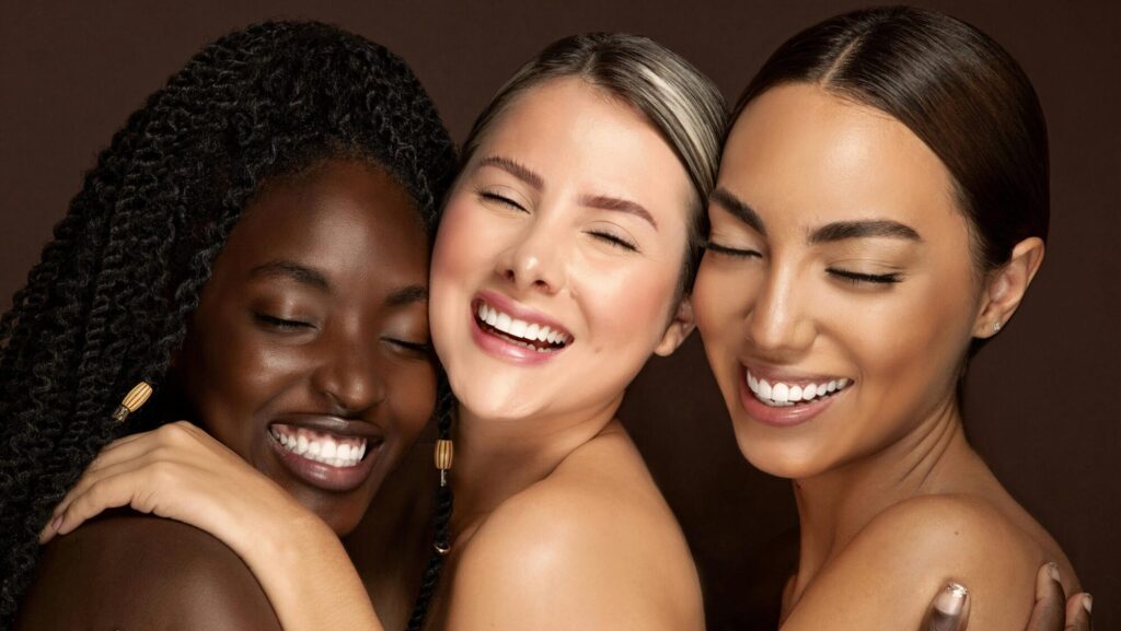 Três mulheres, uma negra, uma branca e uma asiática, representando belezas naturais.