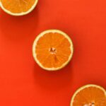 Three juicy orange slices set against a vivid red background, perfect for food-themed designs.