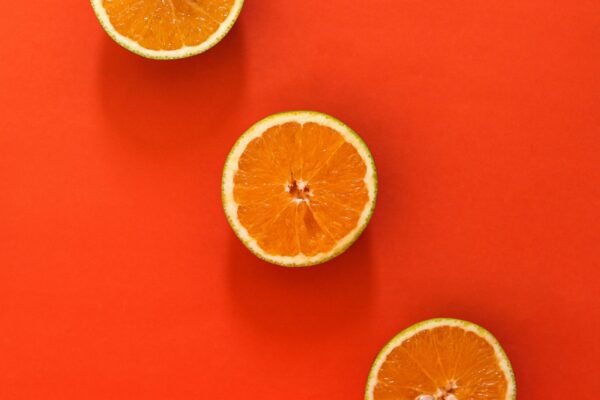 Three juicy orange slices set against a vivid red background, perfect for food-themed designs.